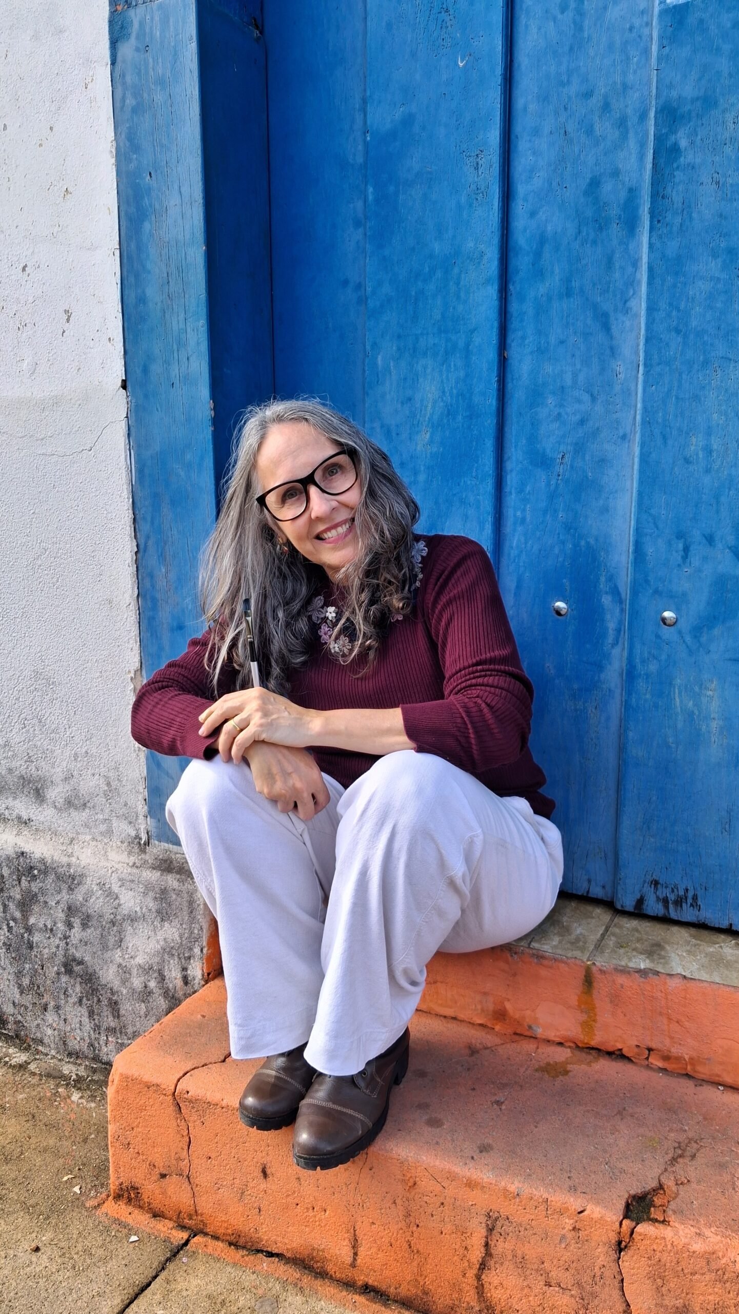 Giselle Vargas diante de uma porta azul